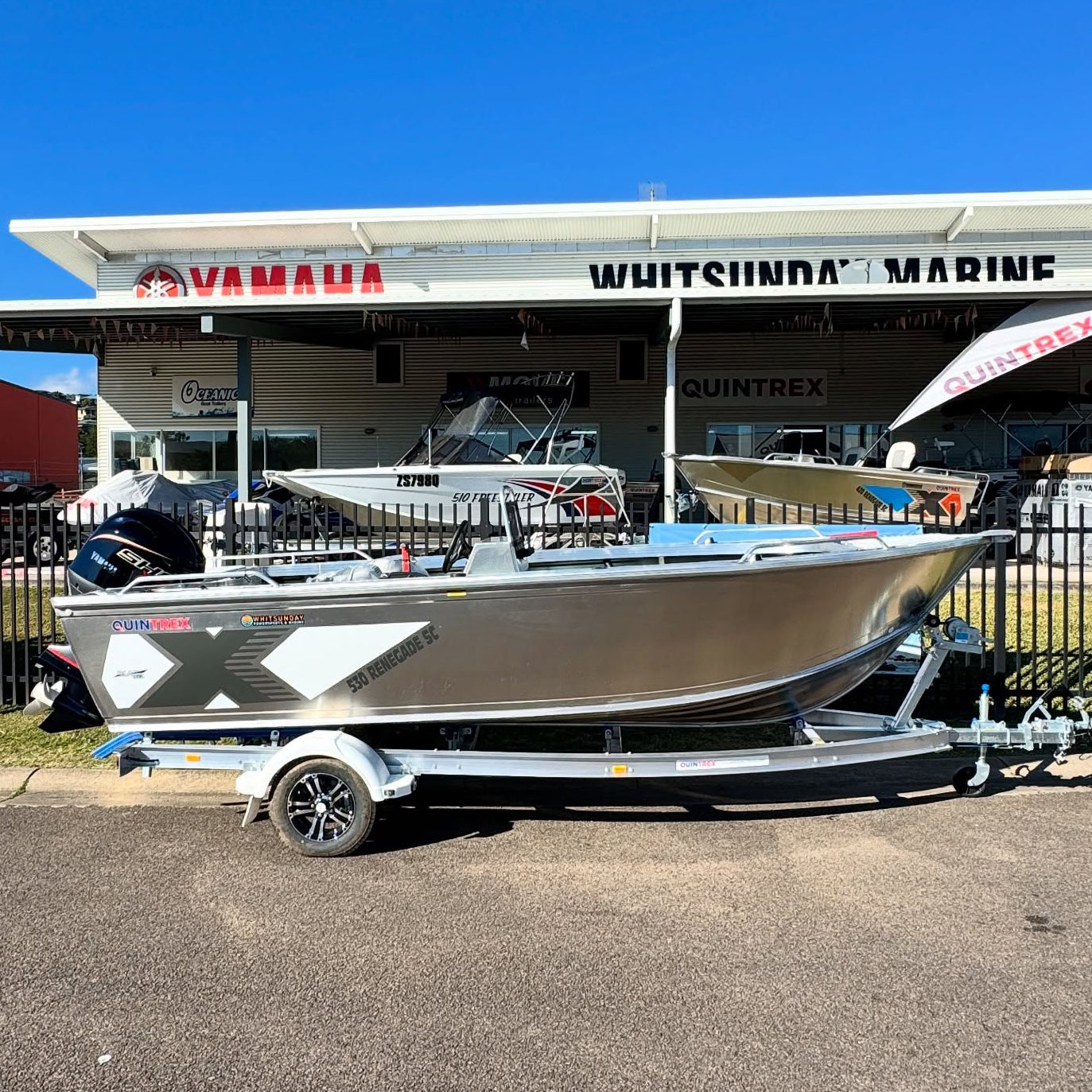 Boat on a trailer in front of a Yamaha and Whitsunday Marine building.